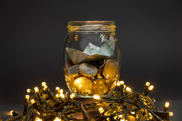 Glass jar with euro coins and paper boat centered on a dark background on top of led lights. Euro...