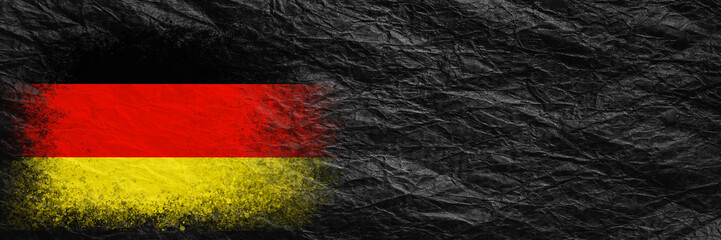 Flag of Germany. Flag is painted on black crumpled paper. Paper background. Copy space. Textured background