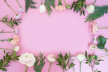 View from above. Close-up of a frame of fresh flowers rose, ranunculus, carnation, juniper, eustoma, bush chrysanthemum, on a pink background. With a space to copy. High quality photo