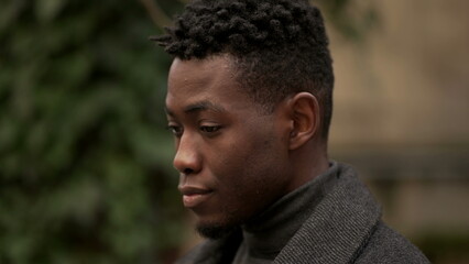 Handsome young black man standing outdoors thinking