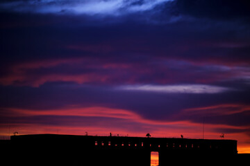 Silhouette of a broken forgotten factory on the background of sunset or sunrise
