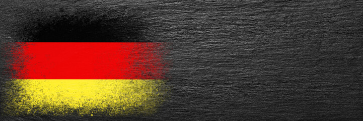 Flag of Germany. Flag is painted on black slate stone. Stone background. Copy space. Textured background