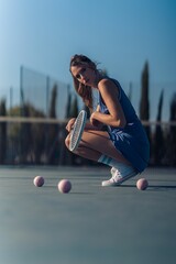 Vertical closeup of a tennis player popping on the tennis court, balls, racquet on hand