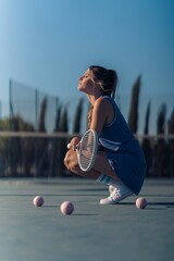 Vertical closeup of a tennis player popping on the tennis court, balls, racquet on hand