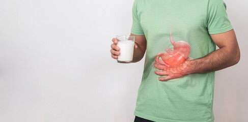 Lactose intolerance. An unrecognizable young man holds a glass of milk in his hand and suffers from...