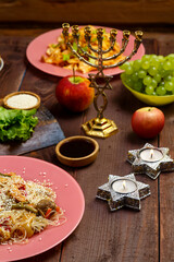 Traditional Jewish dishes on the laid table, candles and menorah.