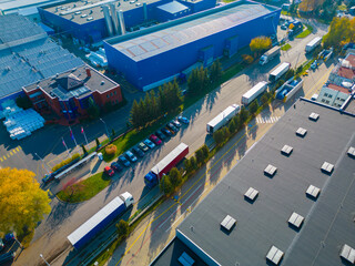 Aerial view of goods warehouse. Logistics center in industrial city zone from above. Aerial view of trucks loading at logistic center