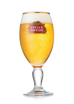 LONDON, UK - AUGUST 10, 2022: Stella Artois lager beer in original glass with foam and bubbles on white background.