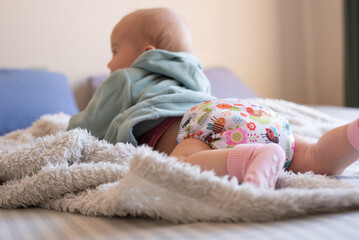 A happy, content baby lying on her stomach doing tummy time to strengthen her back. She is wearing...