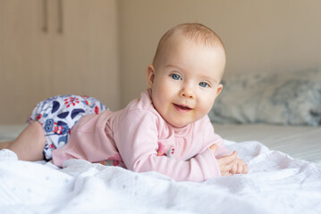 A happy, content baby lying on her stomach doing tummy time to strengthen her back. She is wearing...