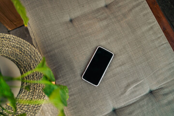 Blank screen mobile phone with copy space on sofa. Flat lay, top view. Copy space mockup template....