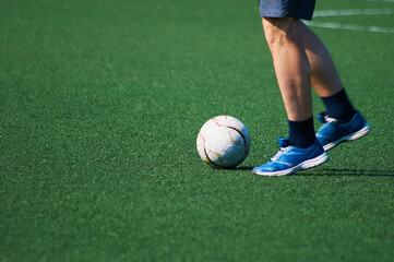 The ball and feet of a soccer player on the green surface of the stadium. game situation. Sunshine. Selective focus. Motion blur.