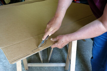 Frau benutzt ein Cuttermesser um eine Form aus einem Karton zu schneiden Camperausbau

frau,...