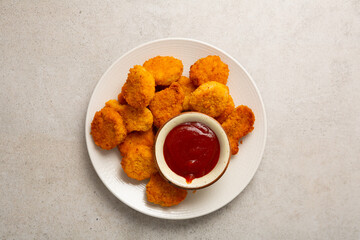Overhead view of chicken nuggets and dip on light surface
