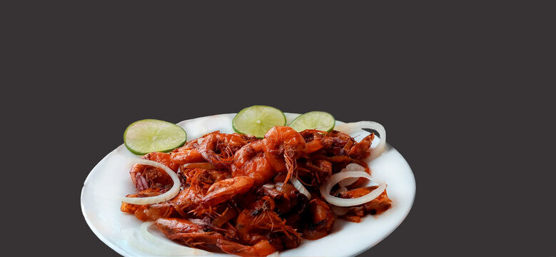 Plate of fried shrimp with onions and lemon on black background with copy space