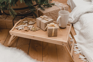 New 2023 2024 year christmas. room ohouse beige shades decorated for holidays. Lots of gifts under Christmas tree and light bulbs. beige tray with New Year's sweets atmosphere of holiday home comfort