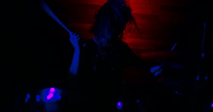 Light turns on, the drummer girl make a trick with drumsticks and begins to play the drums vigorously. Blue and red strobe lights blink to the beat of the drums. The beginning of the show.