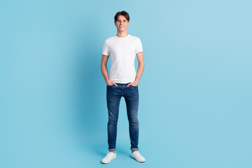 Fototapeta na wymiar Full body picture of casual man with hand in pocket on blue color background