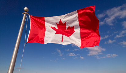 Canadian flag flying at summer blue sky. Canadian flag waving on the wind, unfiltered and natural...