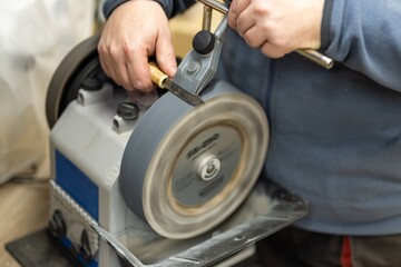 Sharpening knife process, Grindstone close-up. Electric knife sharpening machine. A man sharpens a knife on an electric sander