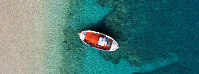 Aerial top view photo of colourful traditional wooden fishing boat anchored in Aegean island...