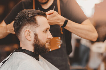 Barbershop concept, vintage color. Portrait happy client man in haircut salon, master does hair...