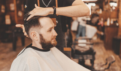 Barbershop concept, vintage color. Portrait happy client man in haircut salon, master does hair...