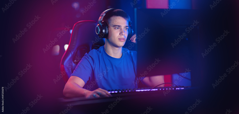 Wall mural Happy Young caucasian man pro gamer streamer play in online video game, neon color soft focus. Concept banner esport tournament