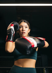 Fototapeta na wymiar A young Asian girl posing with boxing gloves in a guard position, concept of youth boxing, view from below.