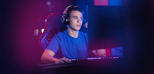Happy Young caucasian man pro gamer streamer play in online video game, neon color soft focus. Concept banner esport tournament - obrazy, fototapety, plakaty