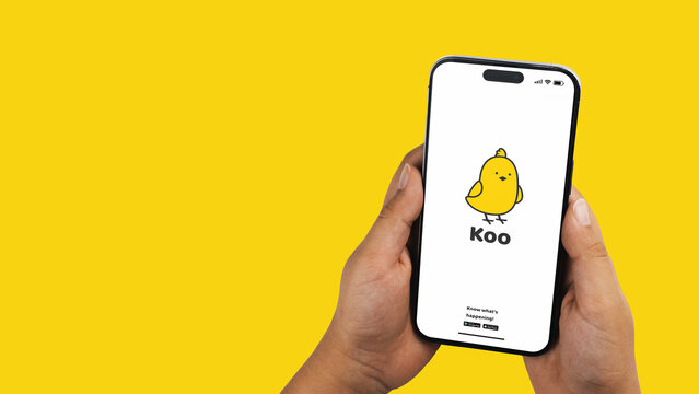 Boy holding a smartphone iPhone 14 Pro with Koo social media app on the screen. Yellow background. Rio de Janeiro, RJ, Brazil. November 2022