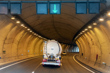 Silo truck for transporting powdery materials circulating inside an illuminated tunnel.
