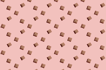 A hard light pattern of sweet cocoa and hazelnut wheat puffed nougat pillows bites - breakfast cereal on pink seamless background