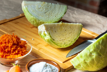 Obraz premium Cabbage on a cutting board, carrot and knife next to it.