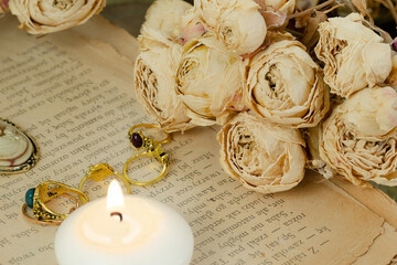 Fototapeta pierścionki, świeczka oraz róże ułożone na starej książce obraz