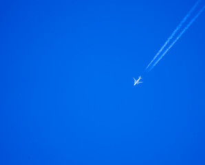 high altitude twin engine contrails (jet airplane vapour trails) across a deep blue clear sky