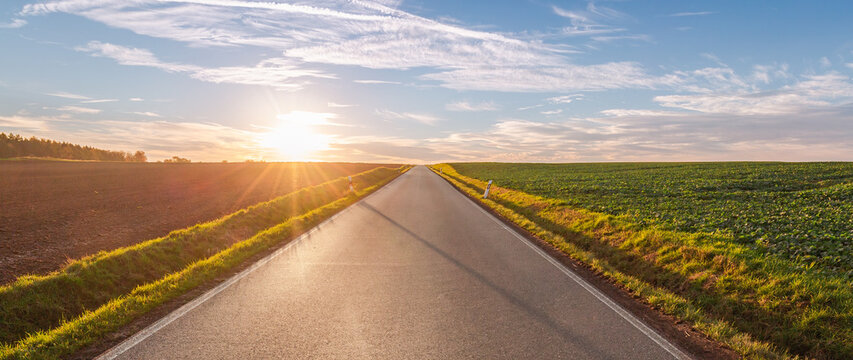 Strait Asphalt Road Going To The Horizon At Sunset