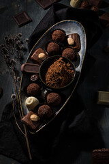 Elegant chocolates assortment scene on a tray over a dark wooden table.