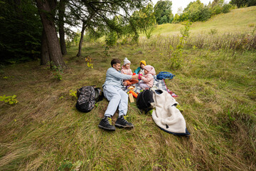 Picnic in autumn park. Father with three kids eat in the forest.