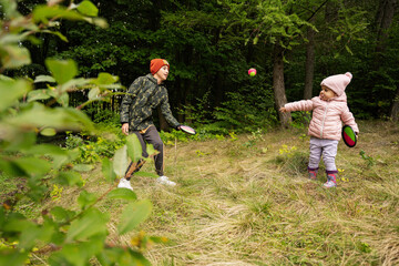 Brother with his little sister play in autumn forest catch and toss ball game.