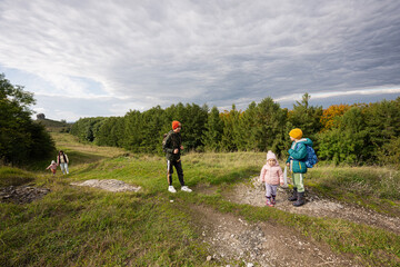 Obraz premium Mother and her kids hiking trough forest.