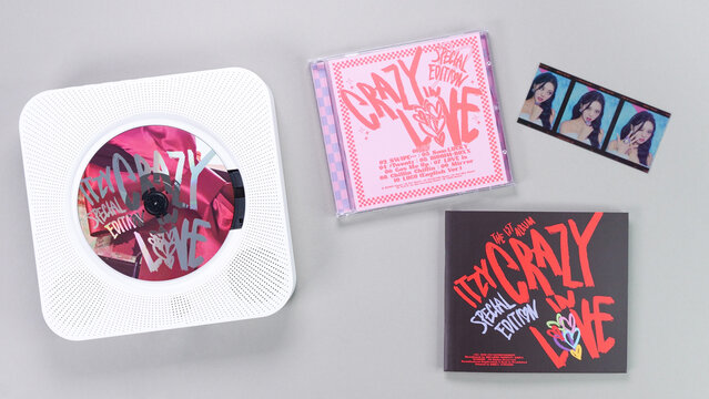 K-pop group Itzy CRAZY IN LOVE 1st Album photobook with photo card on grey. Pink music CD in player. South Korean girl group Itzy. Gatineau, QC Canada - November 10 2022