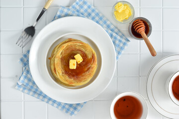 Roti maryam, roti prata, or roti canai are flatbreads or flat pastry originating from India and are commonly found in the Middle East region. Served on plate with butter and honey, for breakfast.