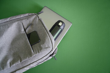 Fashionable urban backpack with laptop, smartphone and thermos. Traveling with gadgets. Hand...