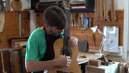 Spanish guitar maker, or luthier, playing a flamenco guitar to test its sound