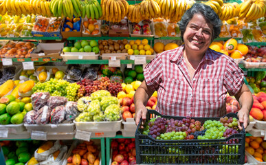Woman with crate of grapes at the fruit market. Selective focus.