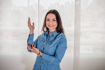 A mulher empreendedora em uma sessão de fotos corporativa em uma pose de pé apontando com a mão...