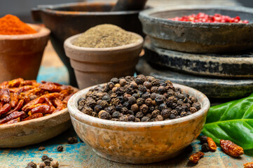 Indian spices collection, dried black peppercorns and another spices in clay bowls