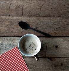 cup of coffee, spoon  and napkin on wooden table
