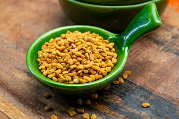 Indian spices collection, dried aromatic fenugreek seeds and another spices in clay green bowl
